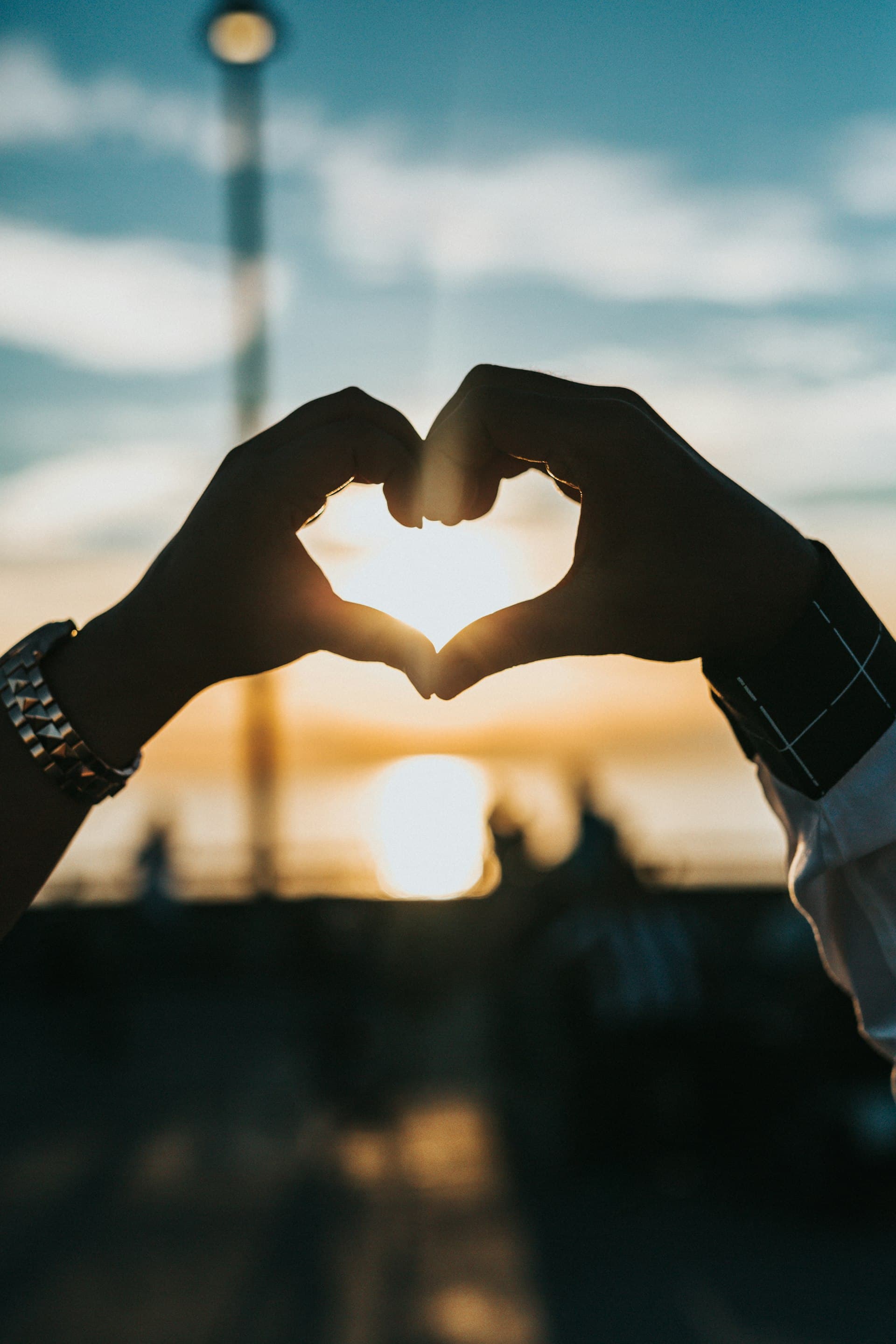 Couple forming a heart with their hands at sunset