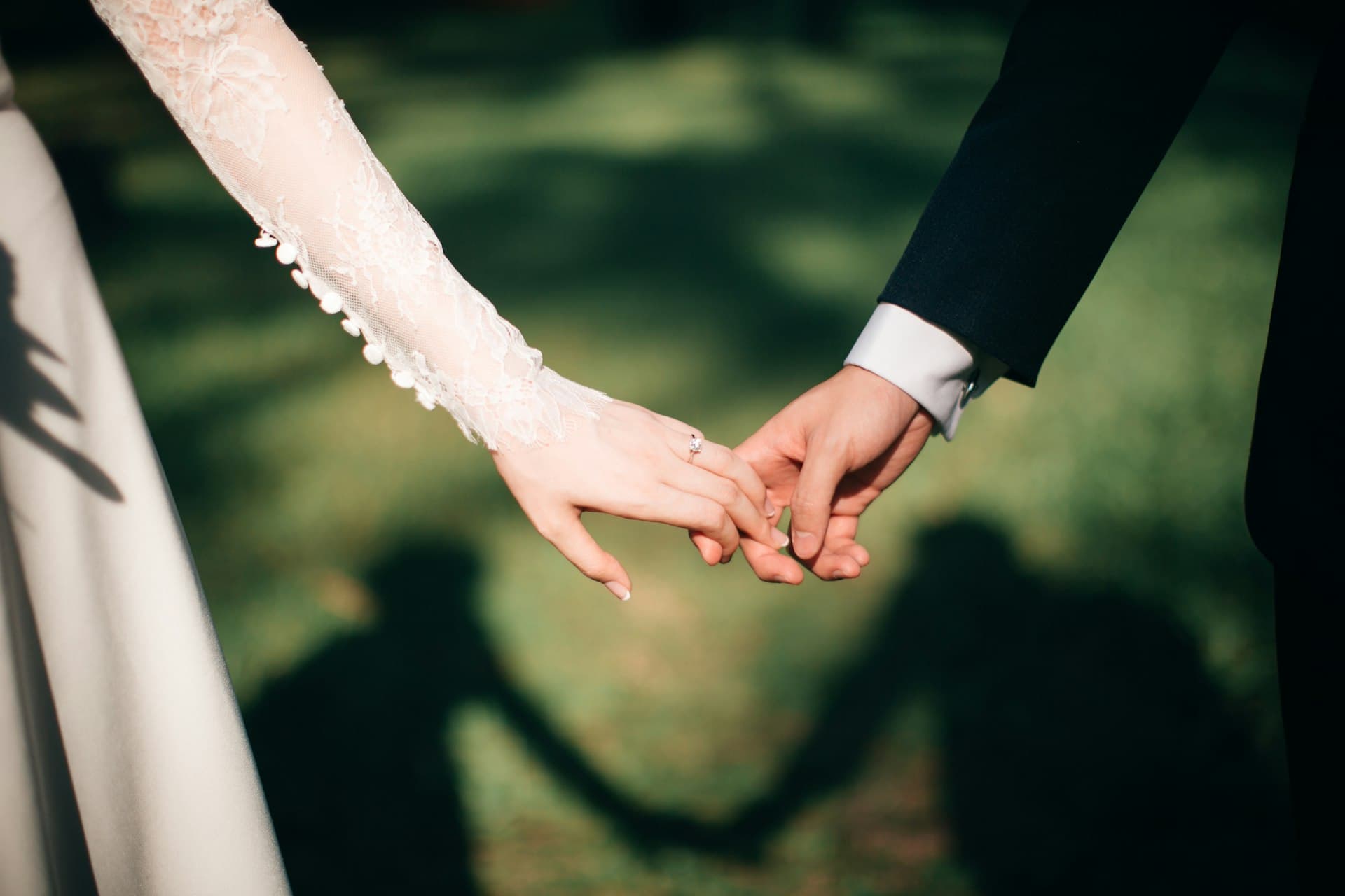Close-up of Western bride and groom holding hands with lace sleeves