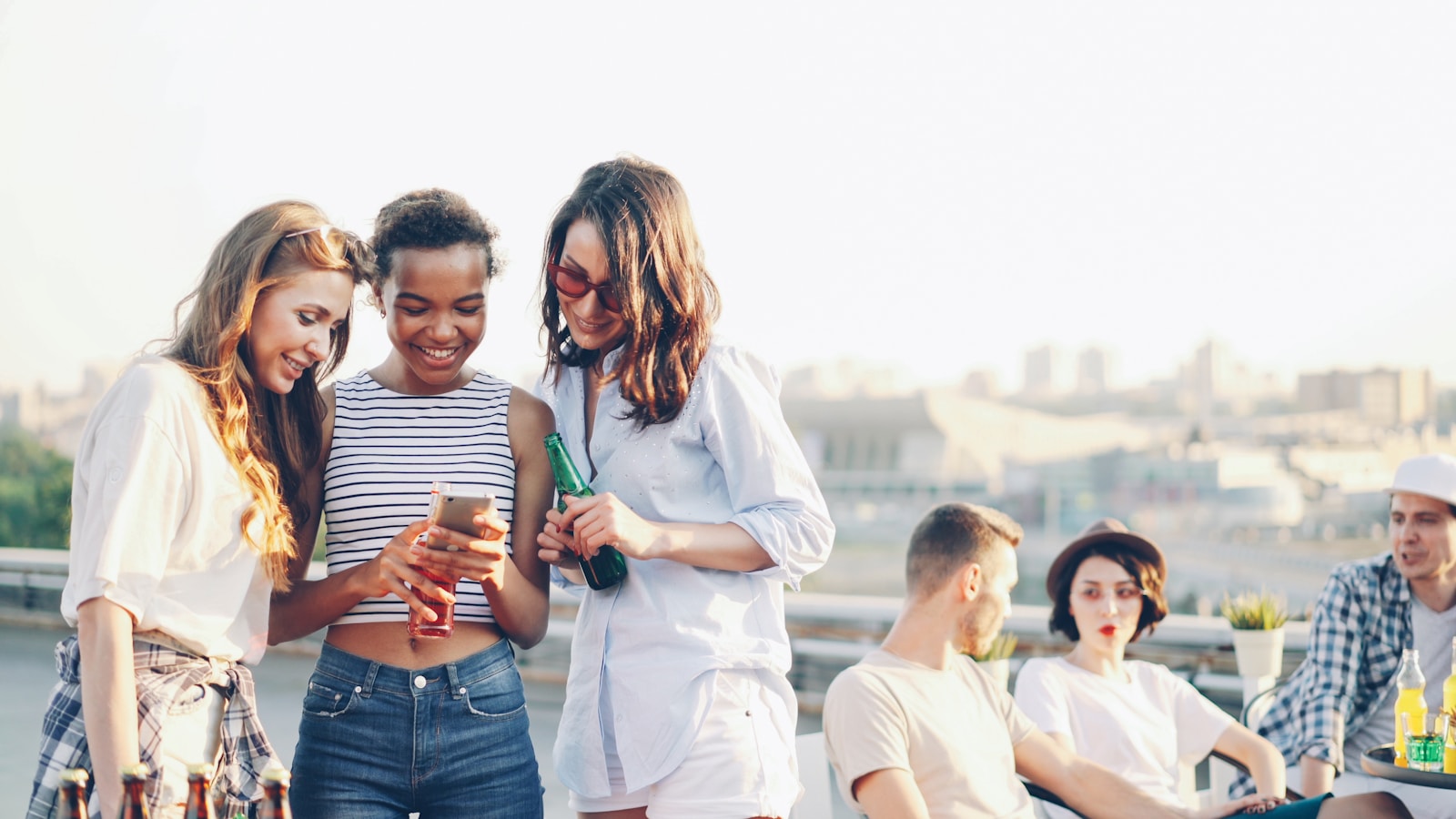 Friends using a smartphone at a lively rooftop event